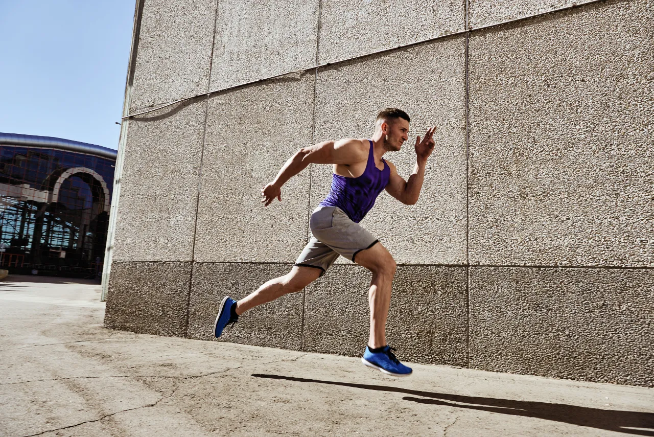 focused strong sporty man running fast on road utc